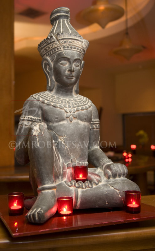 Indonesian statue surrounded by tealights in red glass